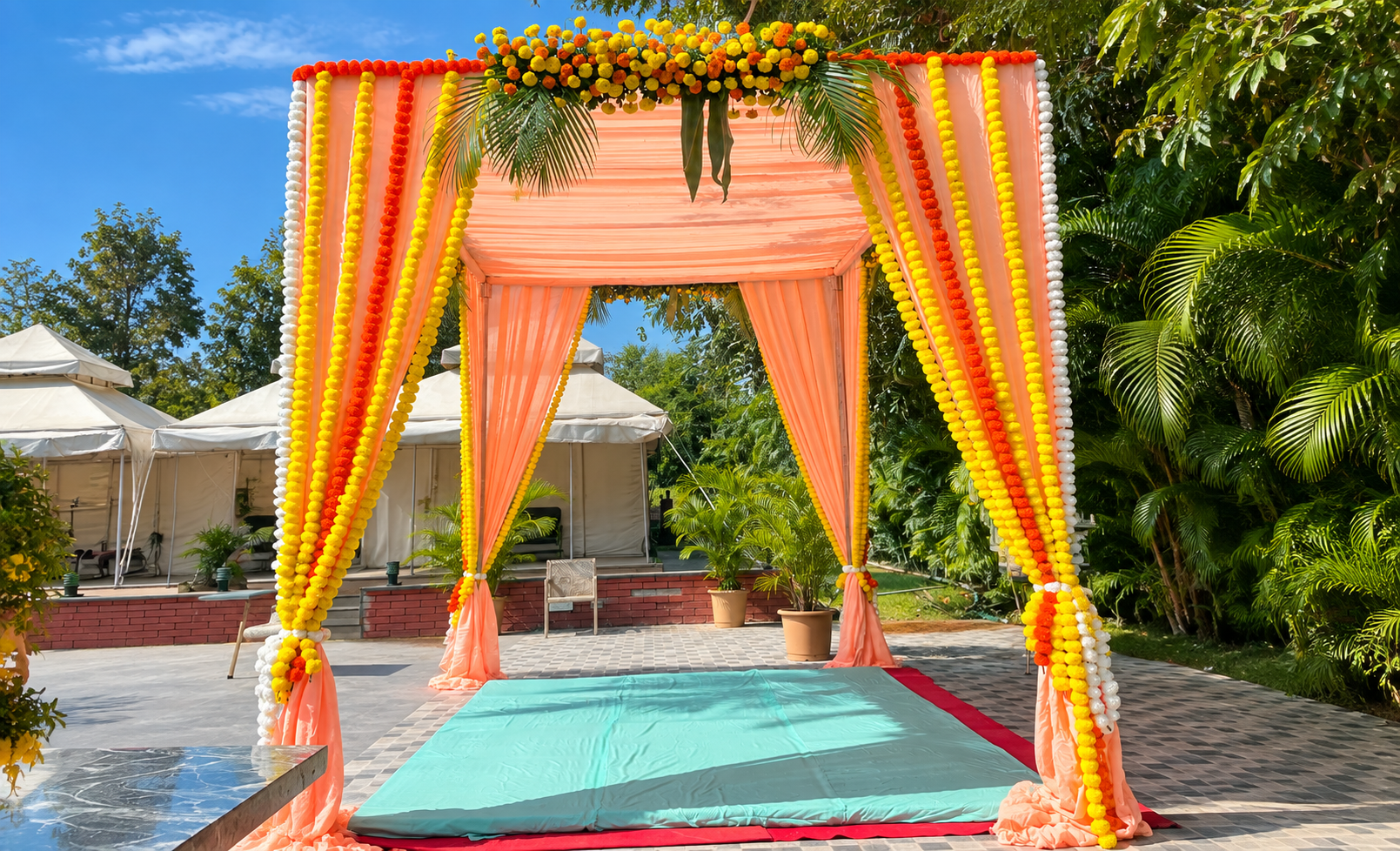 Floral mandap with marigold garlands set up in the resort garden